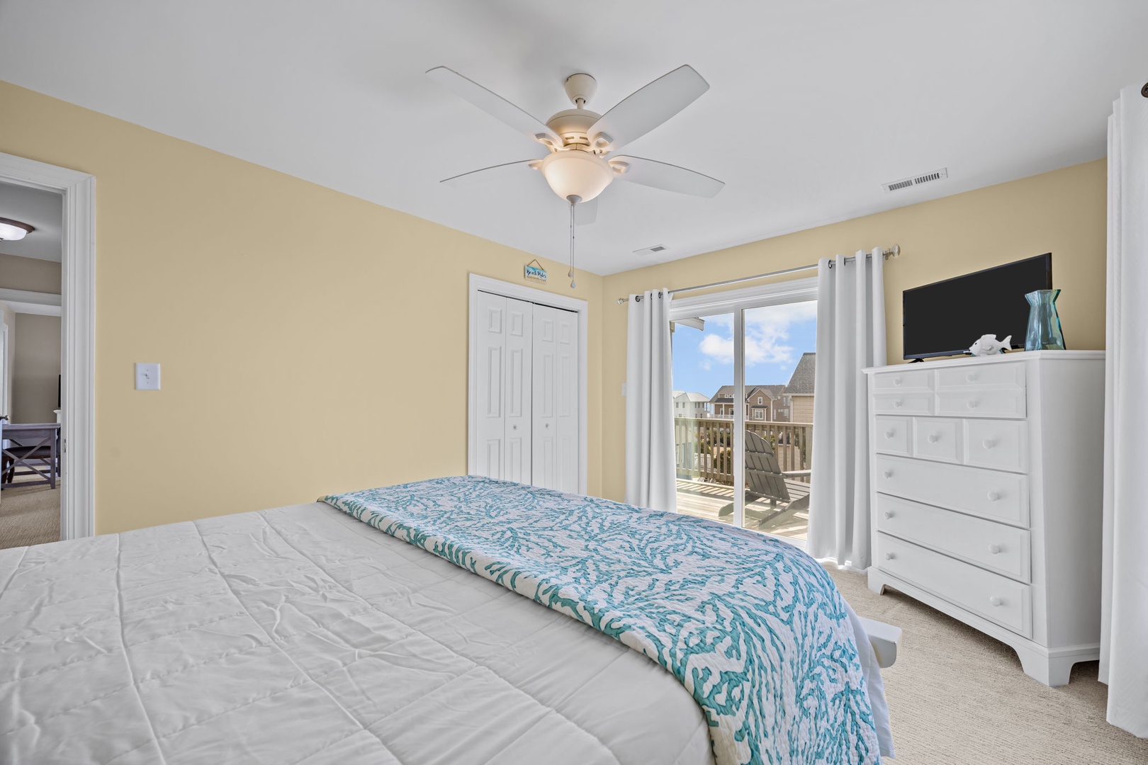 Unwind in your bright bedroom with ocean-themed bedding, ceiling fan, and TV for cozy evenings.