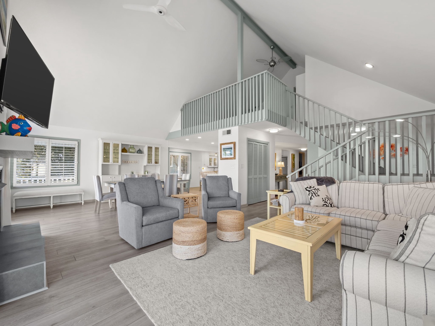 Unwind in this bright, open living space where coastal charm meets modern comfort with stylish furnishings and soaring ceilings.