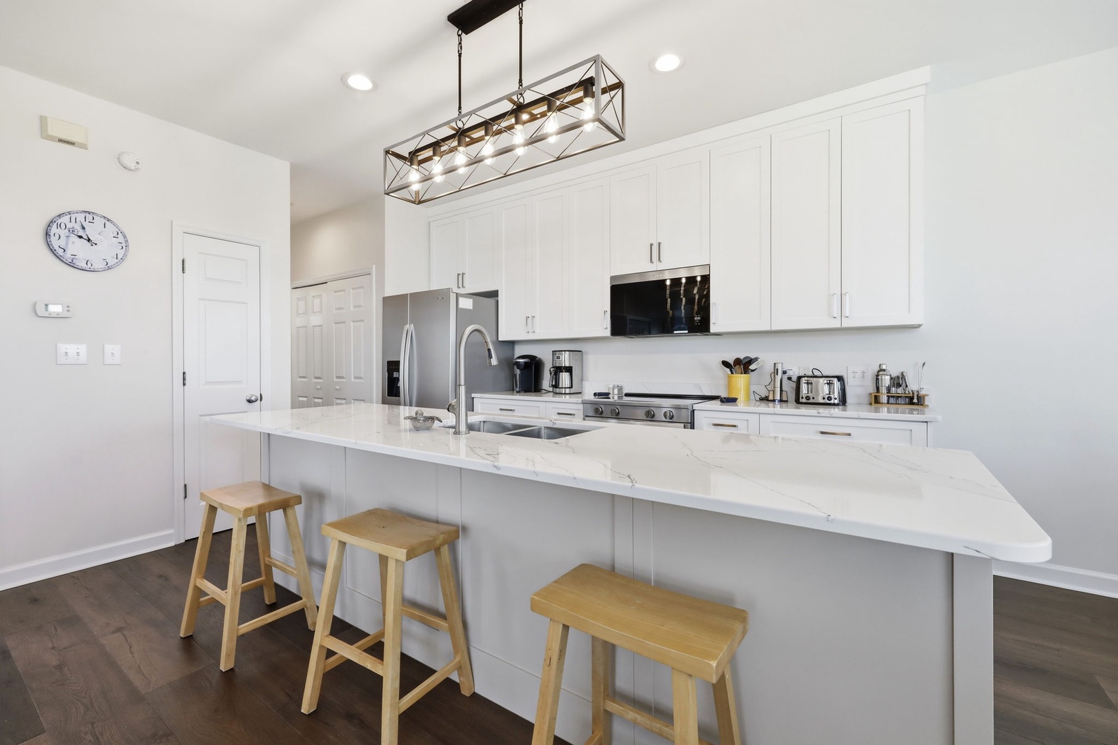 Your bright, modern kitchen features gleaming quartz countertops, stainless steel appliances, and a spacious island perfect for morning coffee or preparing meals during your stay.