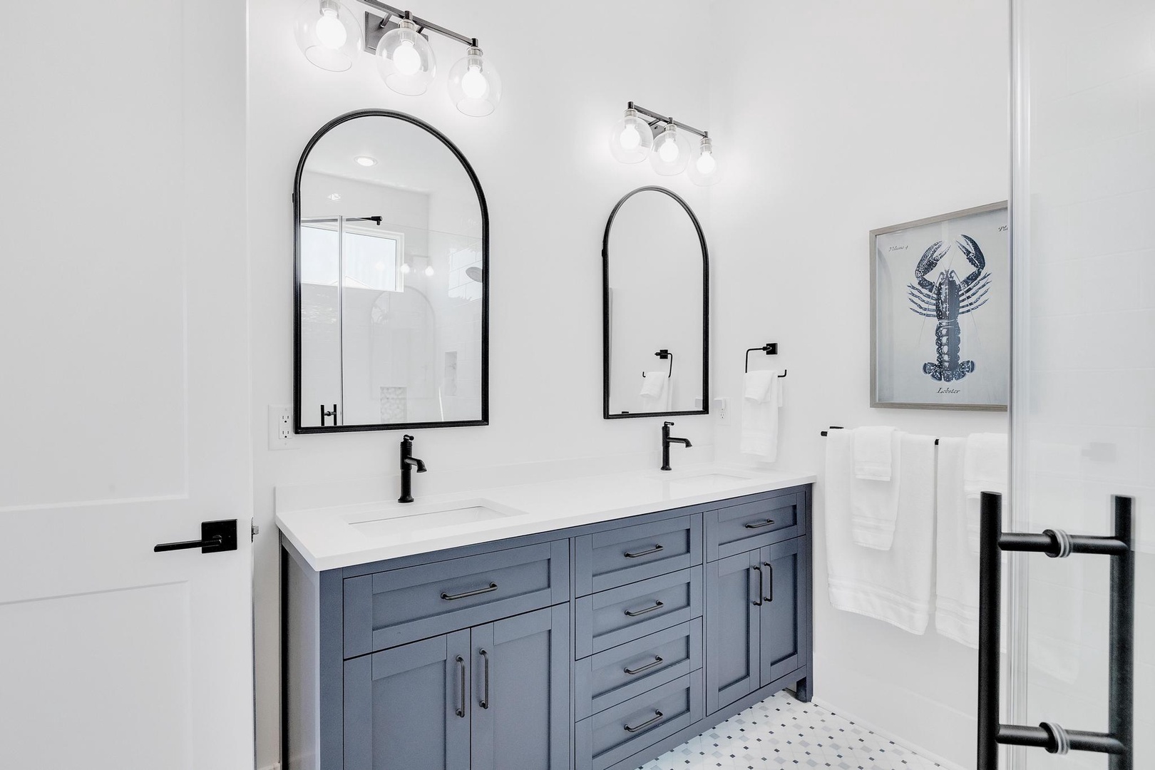 Freshen up in your bright, modern bathroom with double vanity, sleek black fixtures, and coastal-inspired artwork. Your clean white towels are already waiting for you.