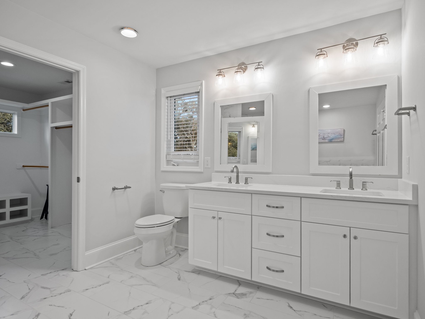 Indulge in your private spa-like bathroom with dual vanities, elegant marble floors, and a spacious walk-in shower for the ultimate morning routine.