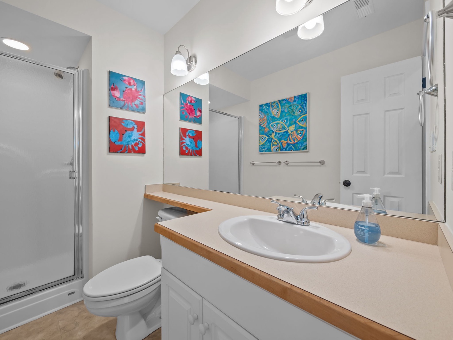 Refresh in your bright bathroom featuring a glass shower, spacious vanity, and cheerful tropical artwork that brightens your morning routine.