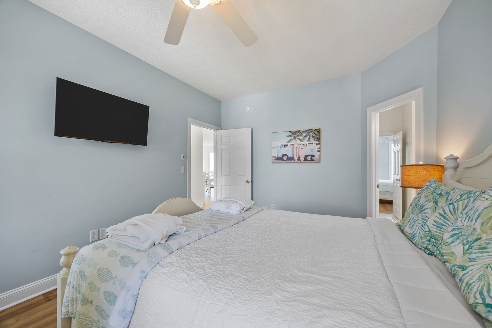 Drift off in this serene bedroom featuring soft blue walls, crisp linens, and tropical touches that create your perfect coastal retreat.
