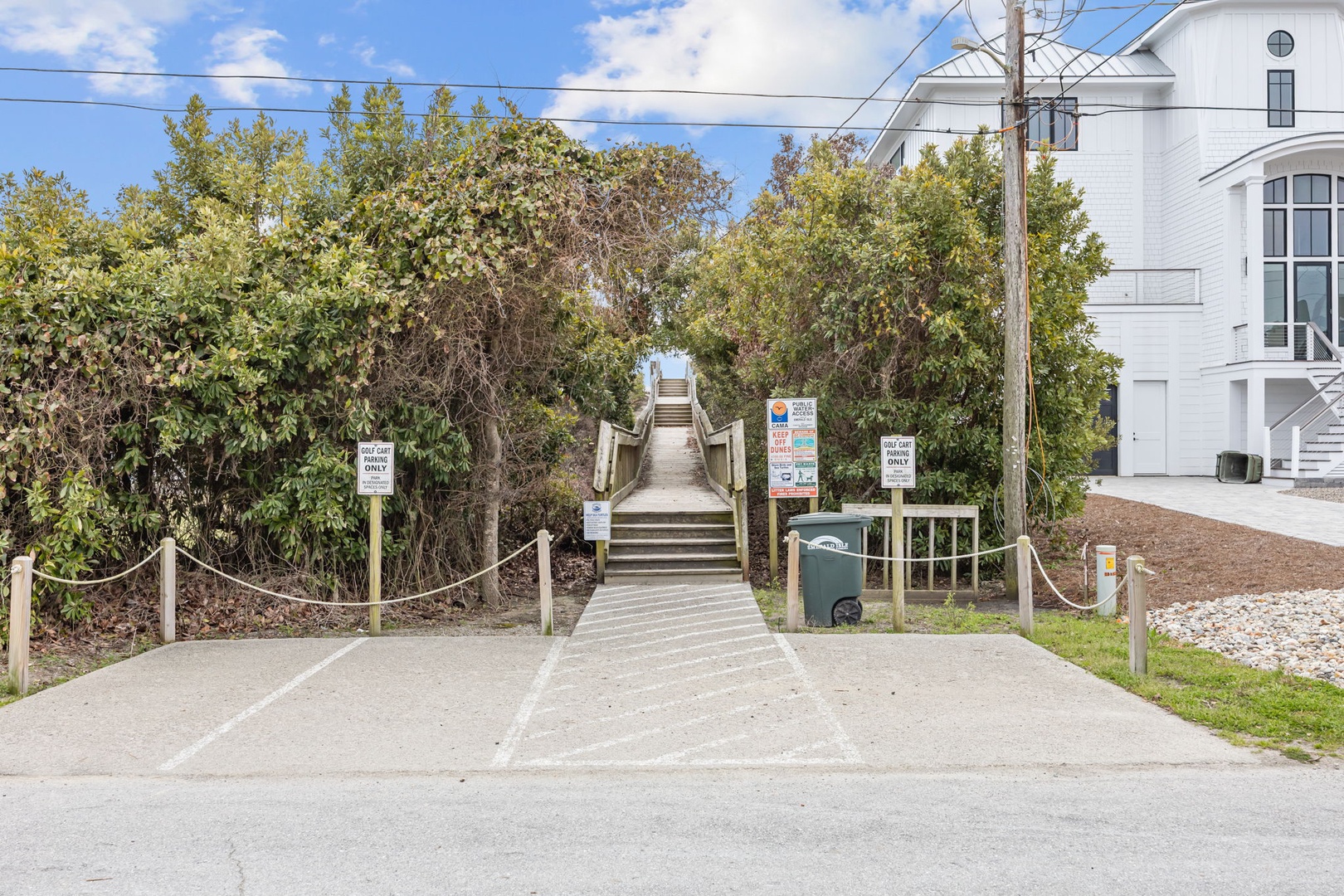 Beach access pathway with wooden boardwalk leading through coastal vegetation near the property.