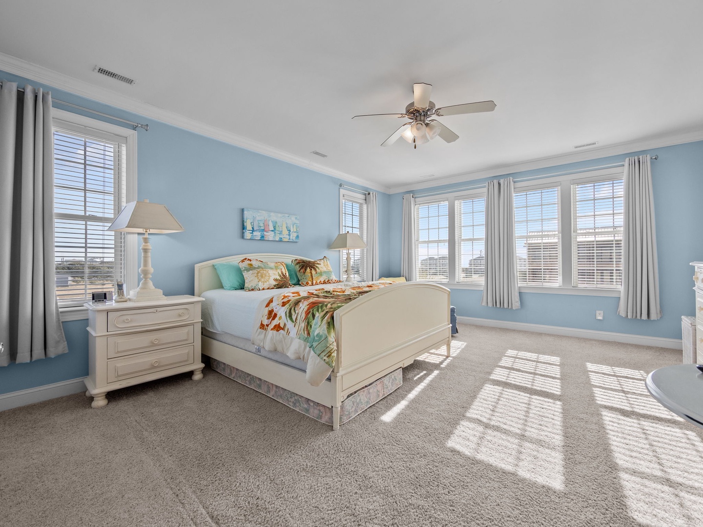 Wake up in this serene coastal bedroom where soft blue walls and natural light create your peaceful retreat.