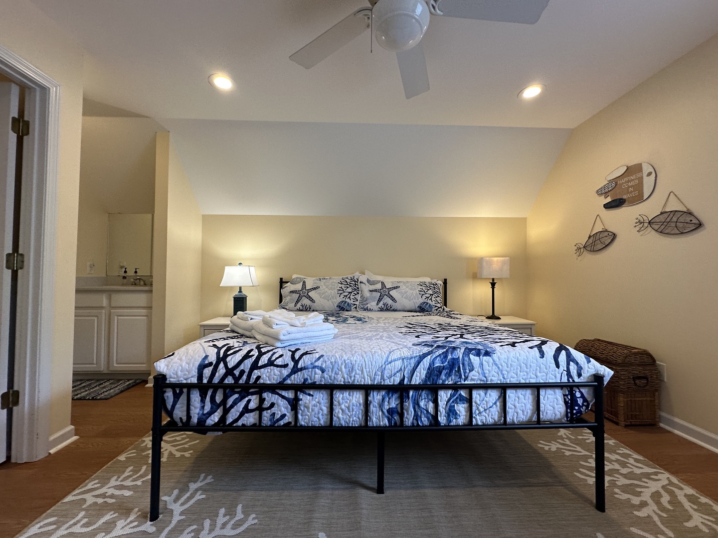 Unwind in your coastal-inspired bedroom with a plush queen bed, ceiling fan, and beachy décor. The en-suite bathroom and soft lighting create a restful retreat.