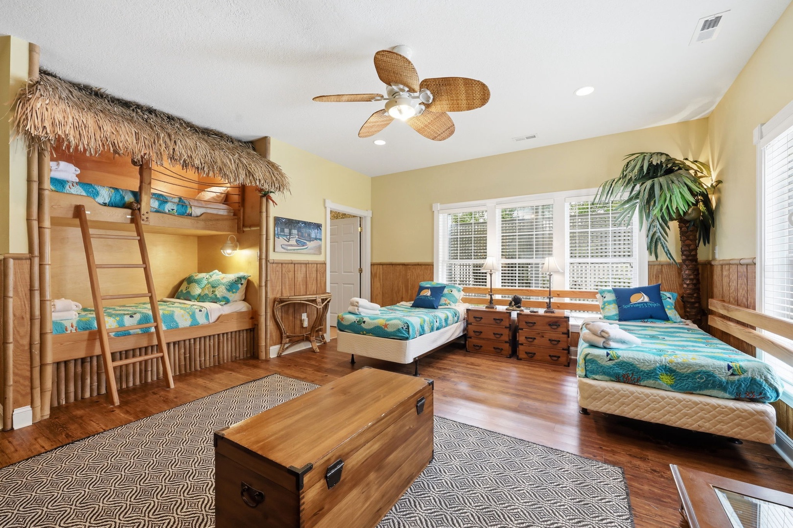 Gather the family in this tropical-themed bedroom featuring a unique bunk bed with thatched canopy and multiple comfy beds—perfect for creating vacation memories together.