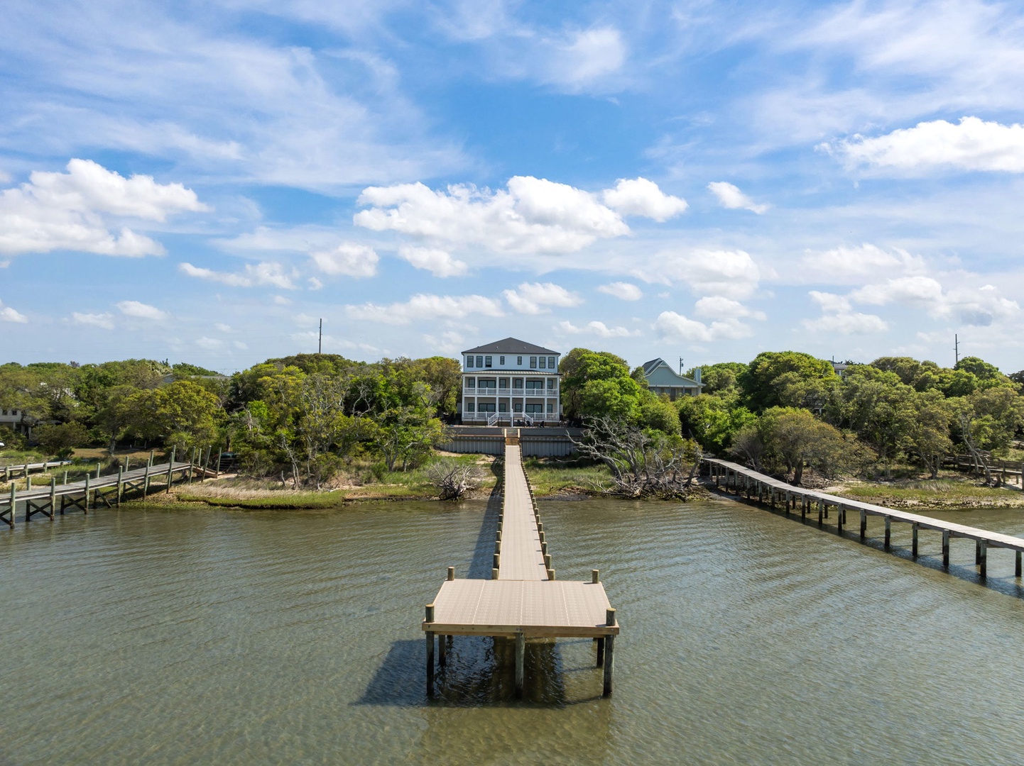 Waterfront property featuring a private dock extending into calm waters, surrounded by lush trees and coastal charm.