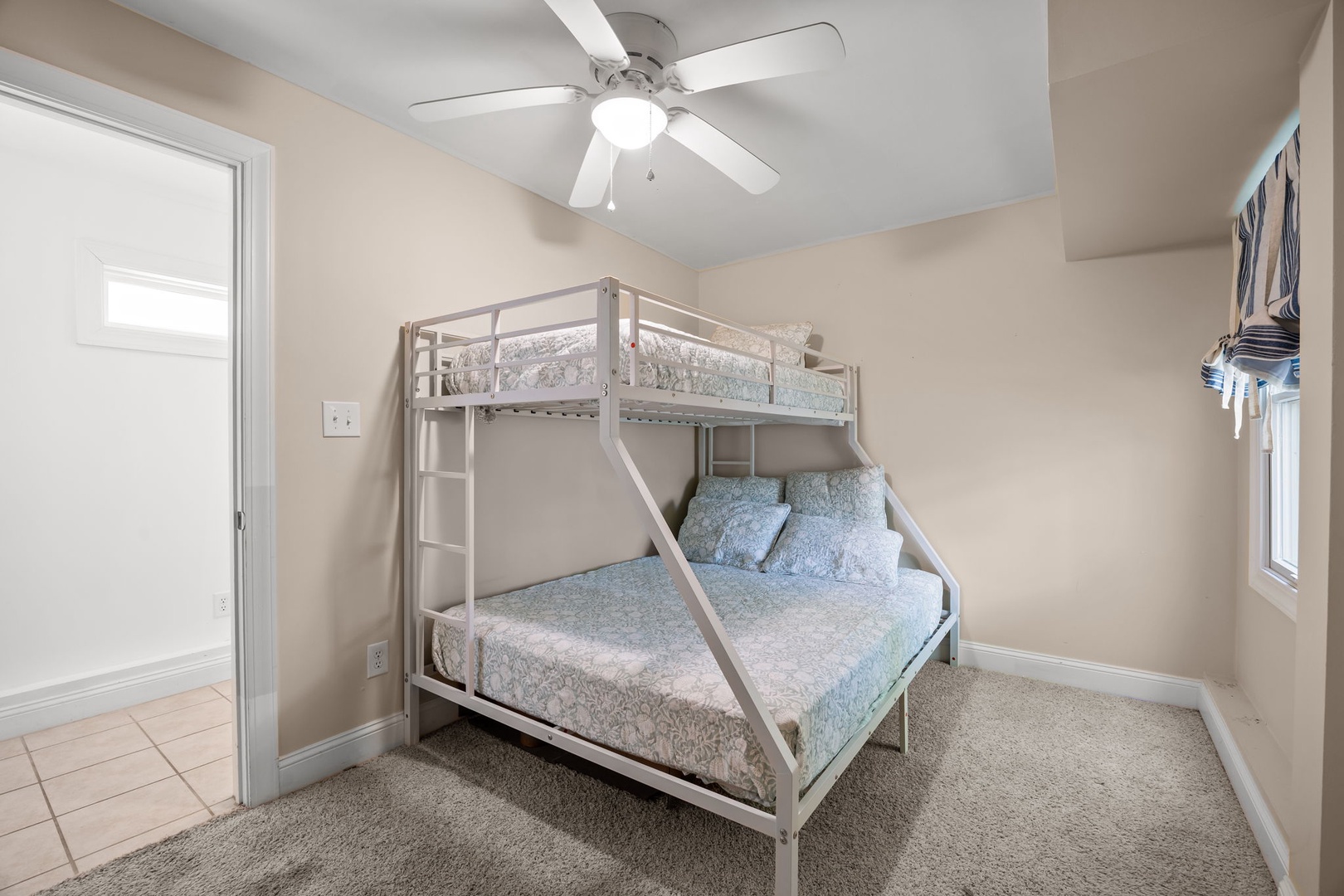 Your comfortable bunk bed setup offers extra sleeping space with soft linens and a ceiling fan to keep you cool.