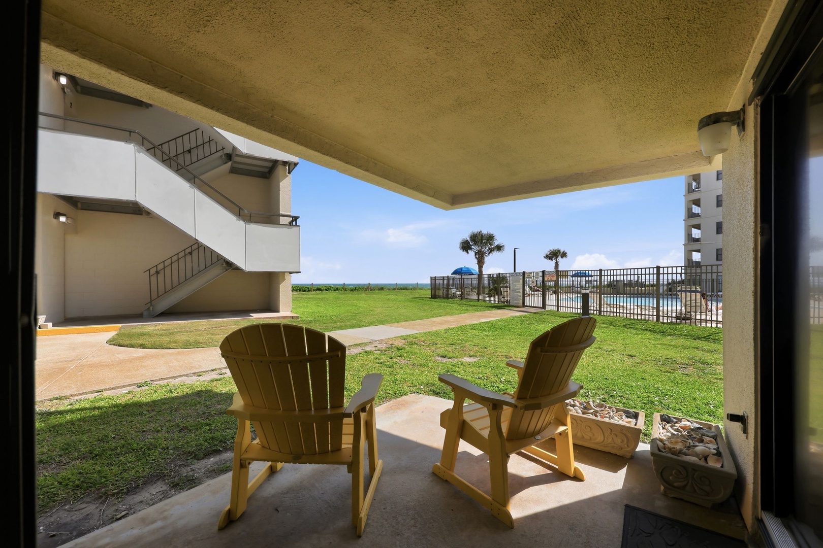 Relax in your own private patio chairs with direct views of lush lawn, swaying palms, and ocean beyond—perfect for morning coffee or sunset watching.