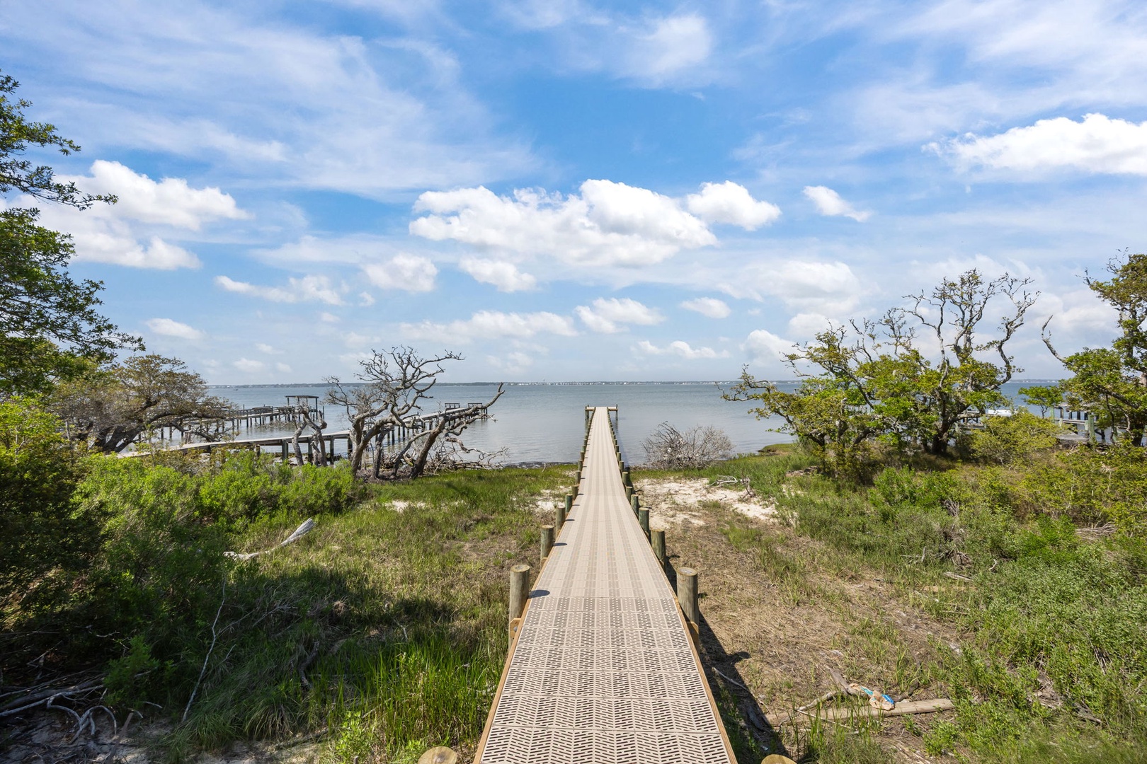 Waterfront location with wooden boardwalk leading to natural coastline, surrounded by native vegetation and peaceful bay views.