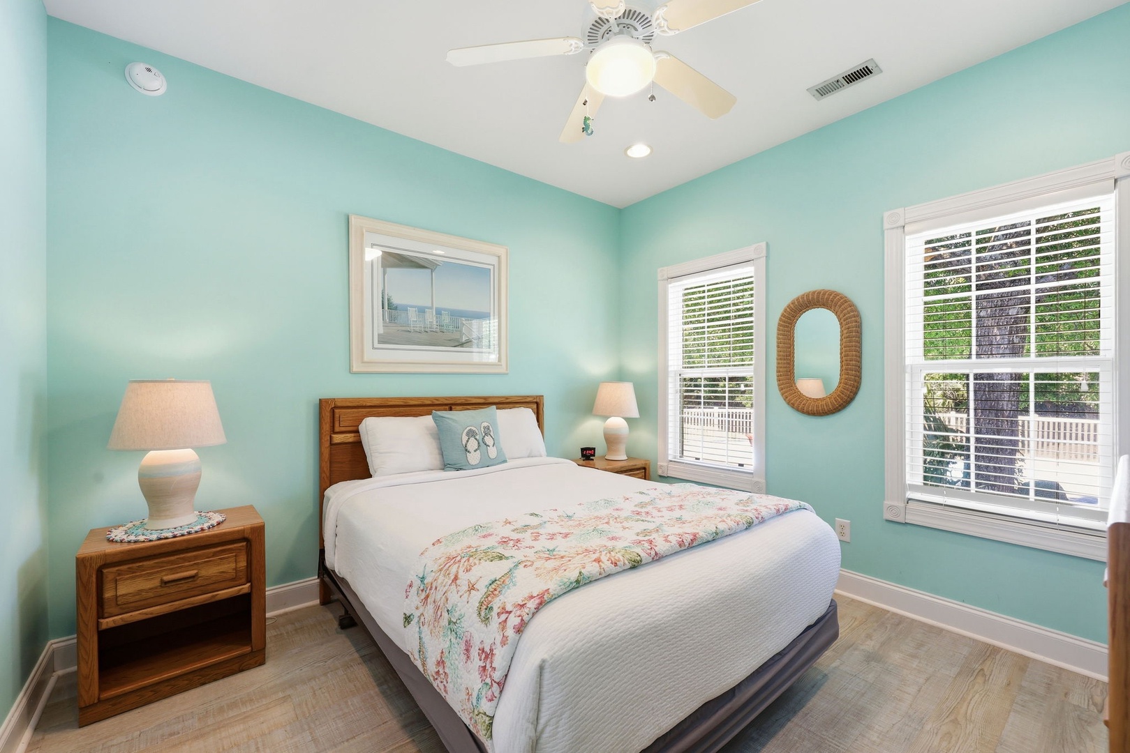 Drift off in your serene coastal bedroom, where soft turquoise walls and warm wood tones create a soothing escape. Natural light pours through plantation shutters framing your peaceful retreat.