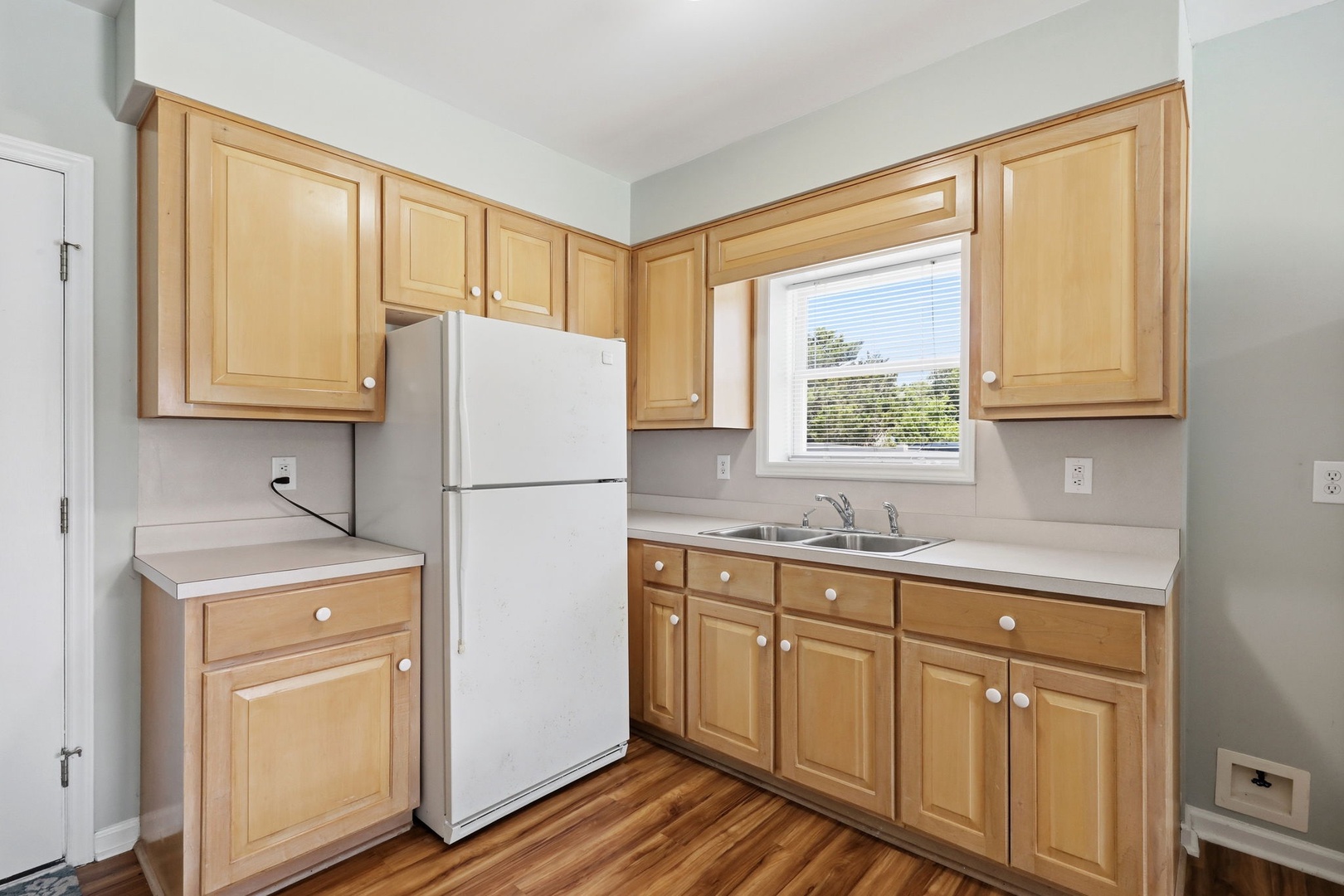 Step into your well-equipped kitchen, where warm wood cabinetry and bright natural light create a welcoming space for preparing meals and gathering with loved ones during your stay.