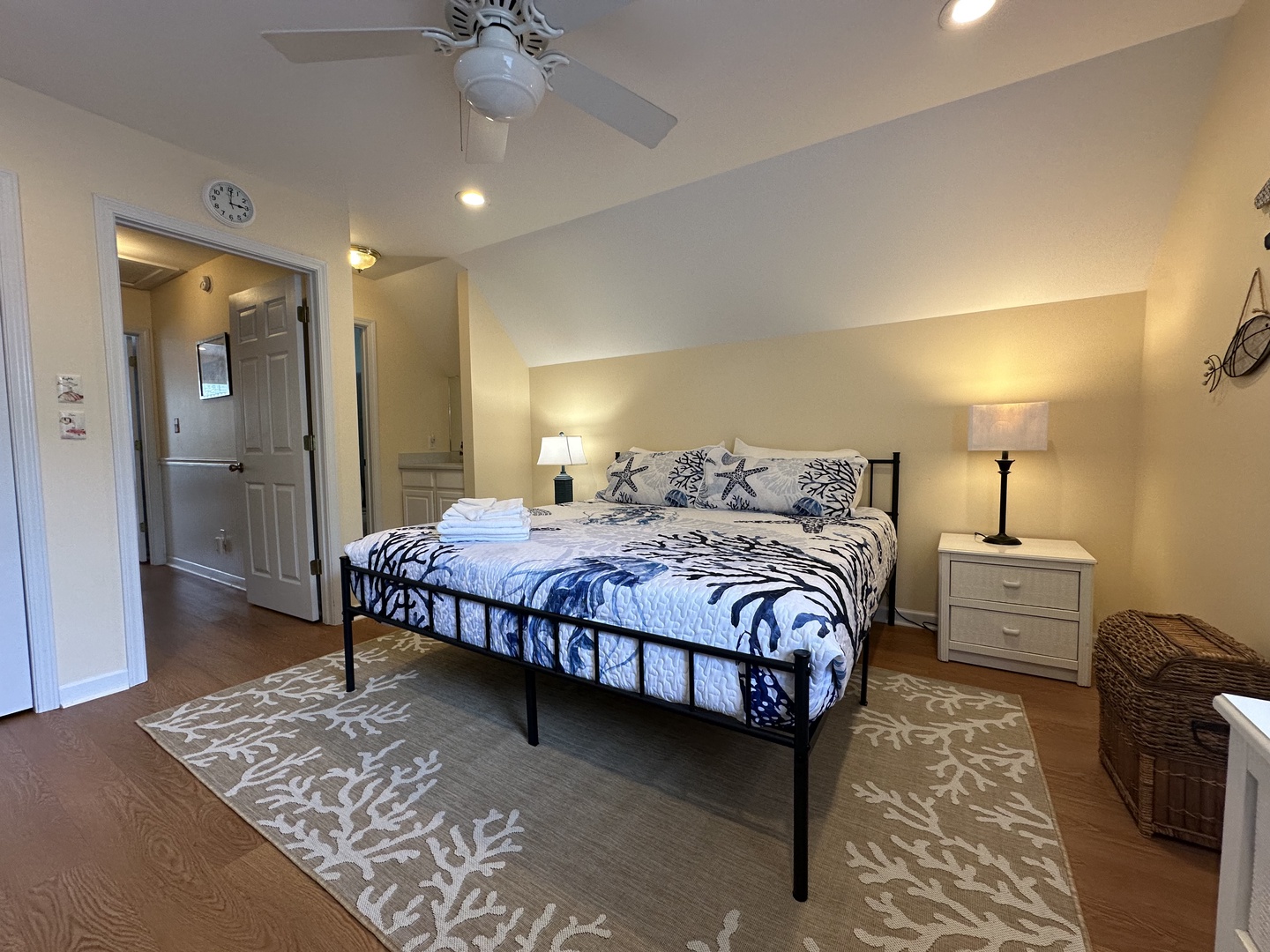 Sink into your plush coastal-themed bed after a long day, where soft linens and a gentle ceiling fan promise restful nights. Your bedside lamps cast a warm glow over polished floors and elegant décor.