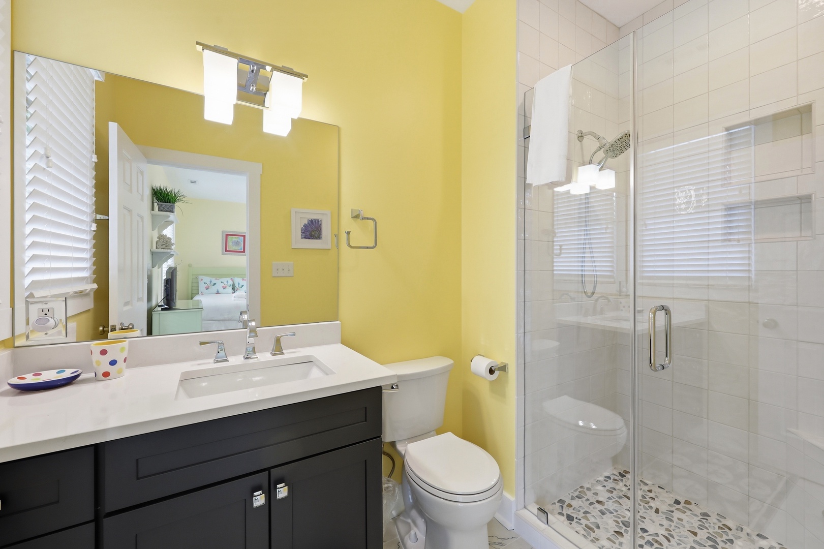 Brighten your mornings in this cheerful bathroom with a spacious walk-in shower, modern vanity, and playful pops of color. Fresh towels and plenty of light await your arrival.