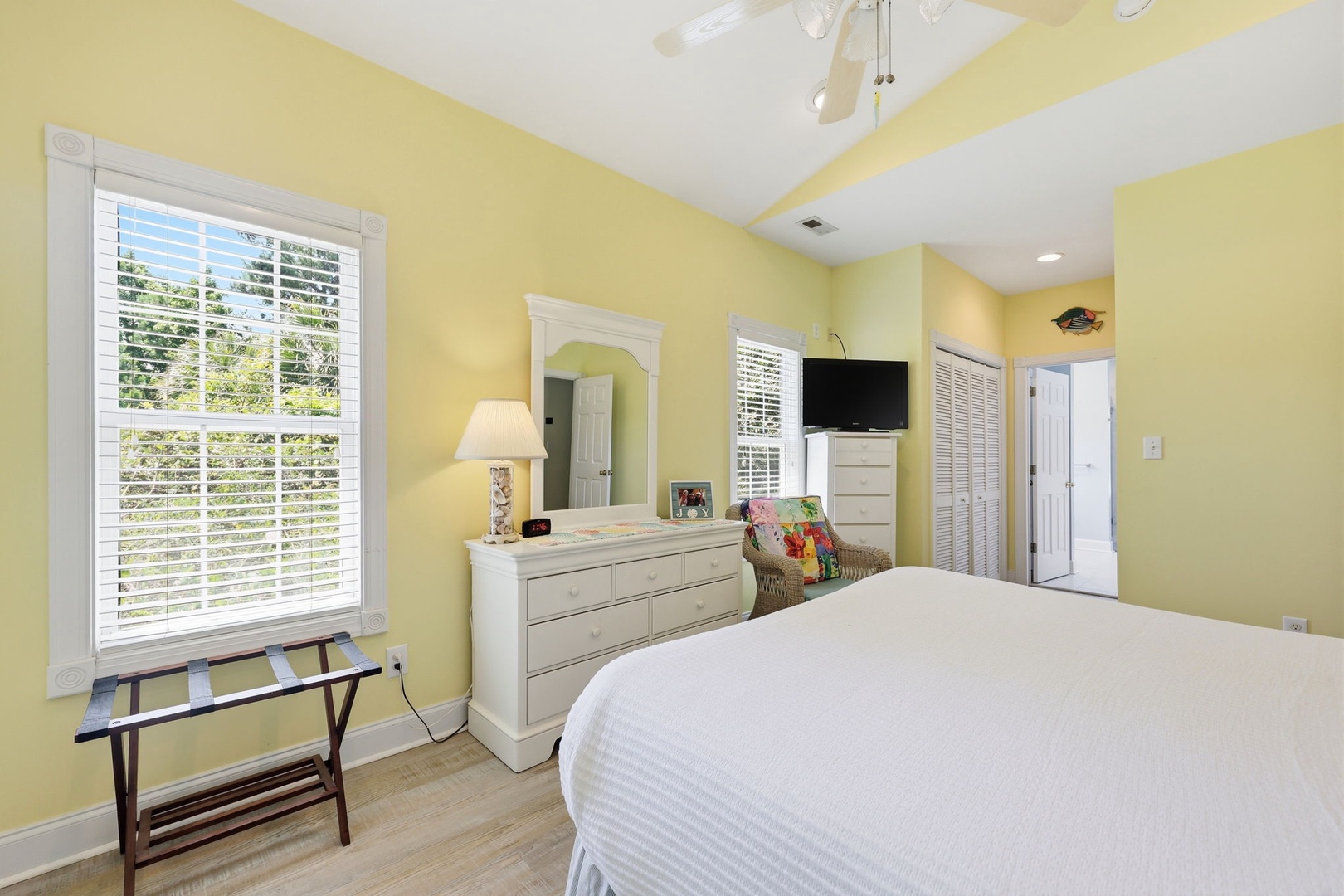 Unwind in your sunny bedroom with vaulted ceilings, a ceiling fan, and bright natural light streaming through plantation shutters. Relax in the inviting coastal decor with modern amenities.