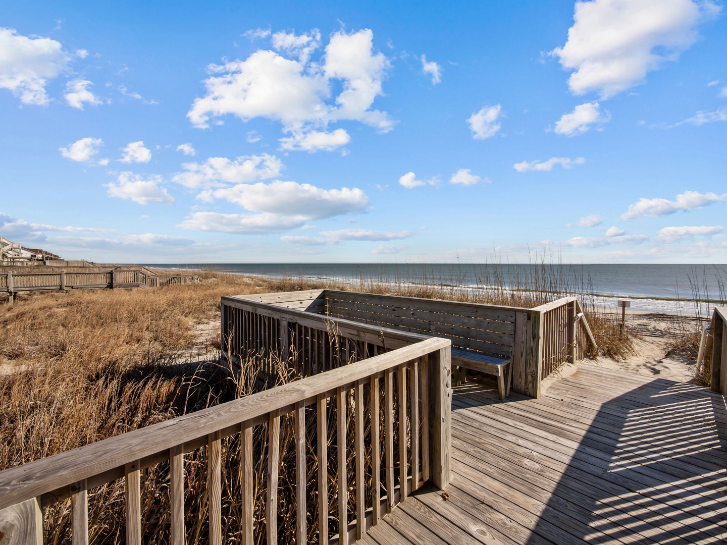 Elevated coastal boardwalk with scenic overlook leads directly to pristine shoreline and expansive ocean views.