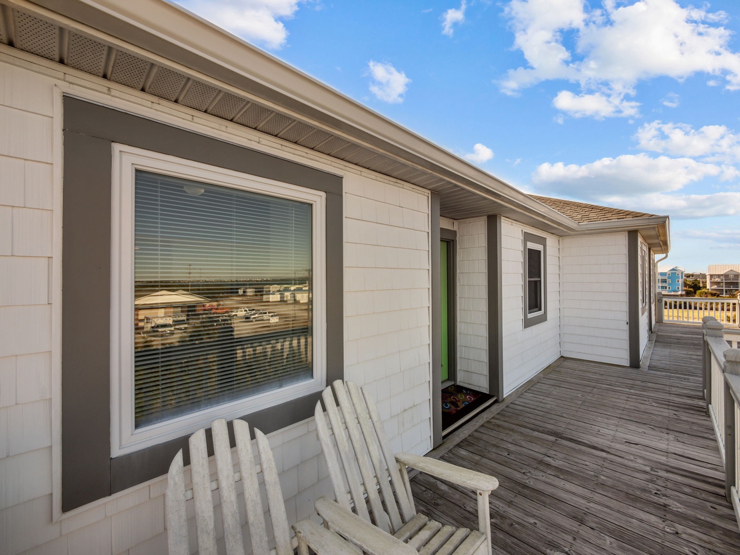Modern beach house exterior features expansive deck with oceanfront views and contemporary coastal design.
