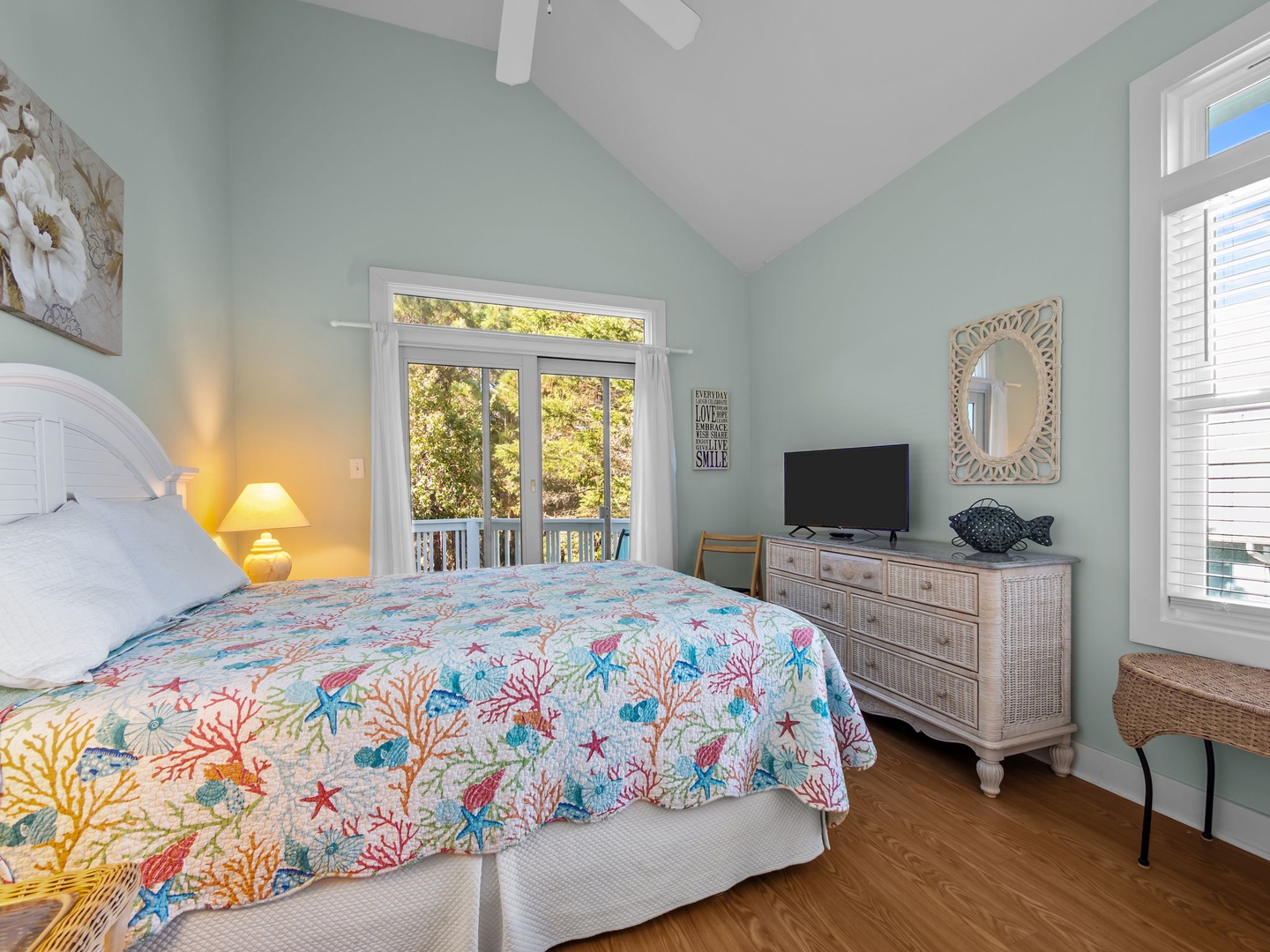 Sink into your coastal-themed bedroom with soft mint walls and cheerful coral bedding, complete with TV and private balcony access.