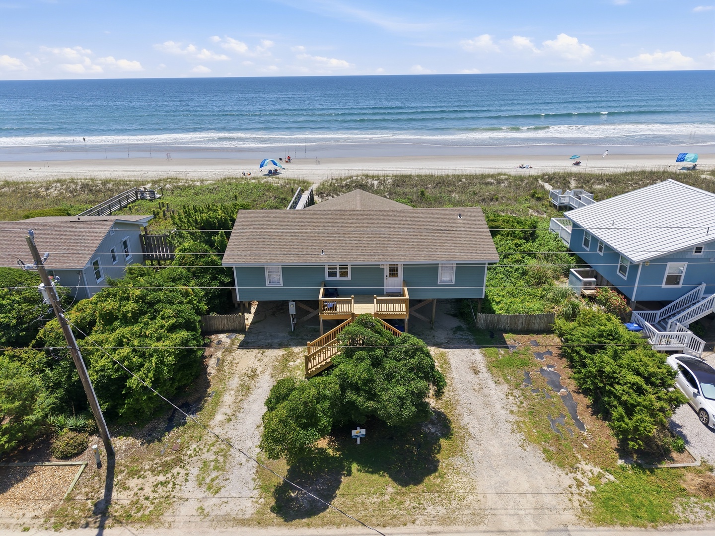 Aerial view showing a beachfront duplex property with direct access to pristine sandy shores and the Atlantic Ocean, surrounded by coastal vegetation and neighboring beach homes.