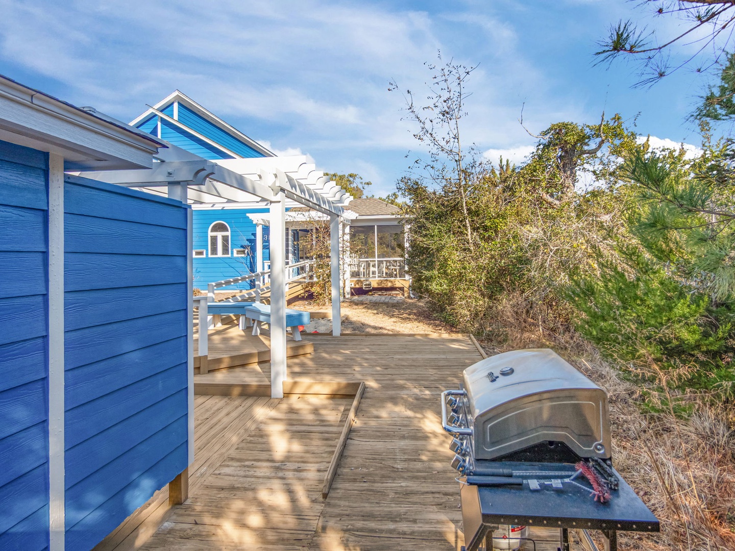 Charming blue cottage with spacious deck and outdoor pizza oven creates the perfect coastal retreat for memorable gatherings.