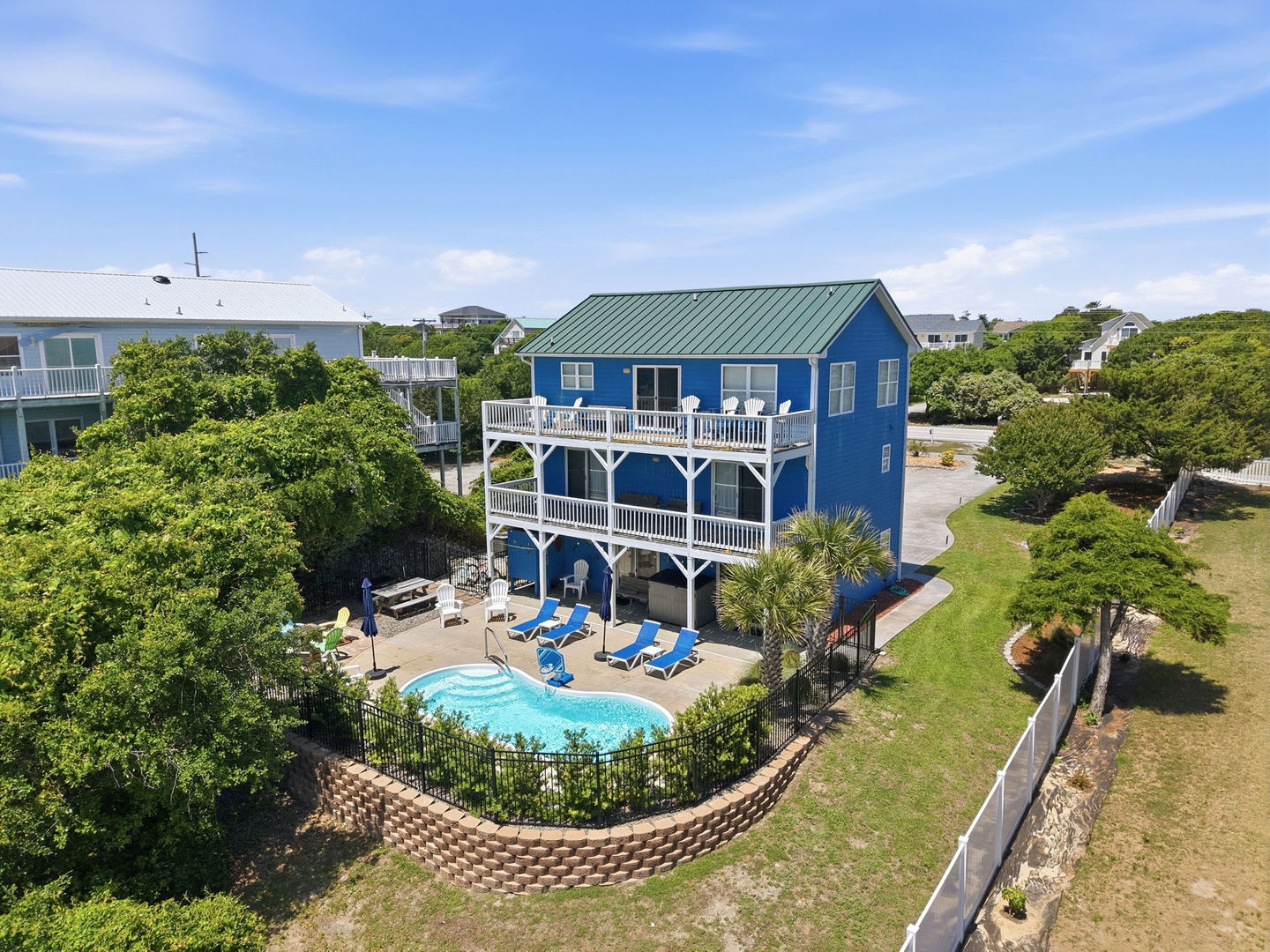 Charming coastal beach house with private pool and spacious multi-level deck, nestled among lush greenery in a quiet residential neighborhood, just moments from the shore.