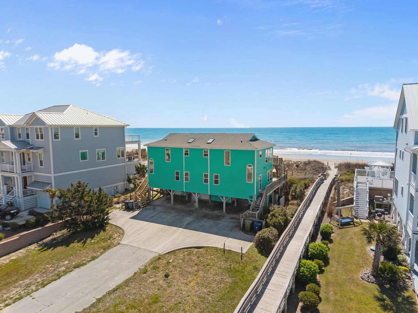 Bright turquoise beachfront home with boardwalk access to pristine sandy shores and crystal-clear ocean waters.