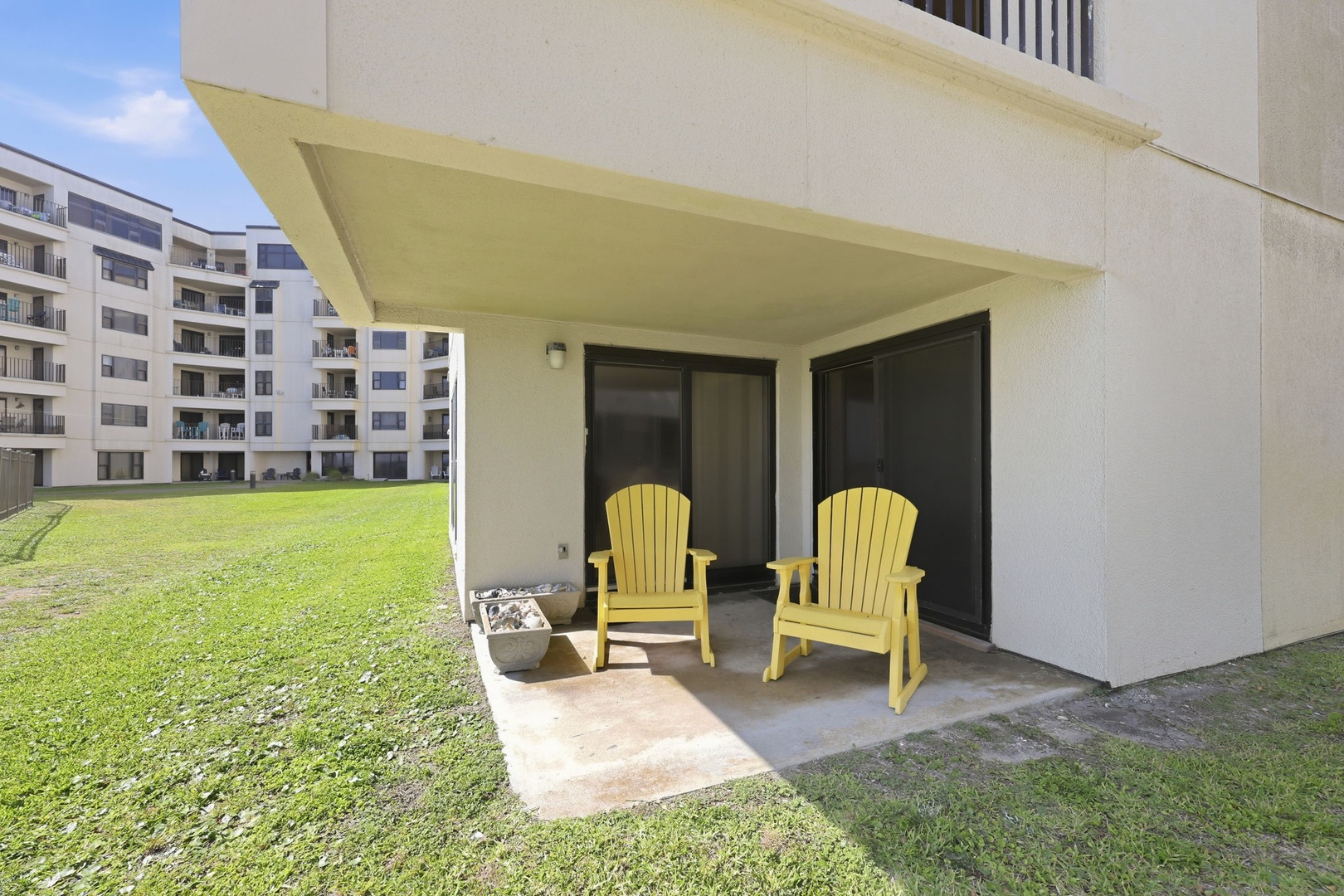 Unwind on your private covered patio with cheerful Adirondack chairs overlooking lush green lawns—perfect for morning coffee or evening relaxation in your peaceful retreat.