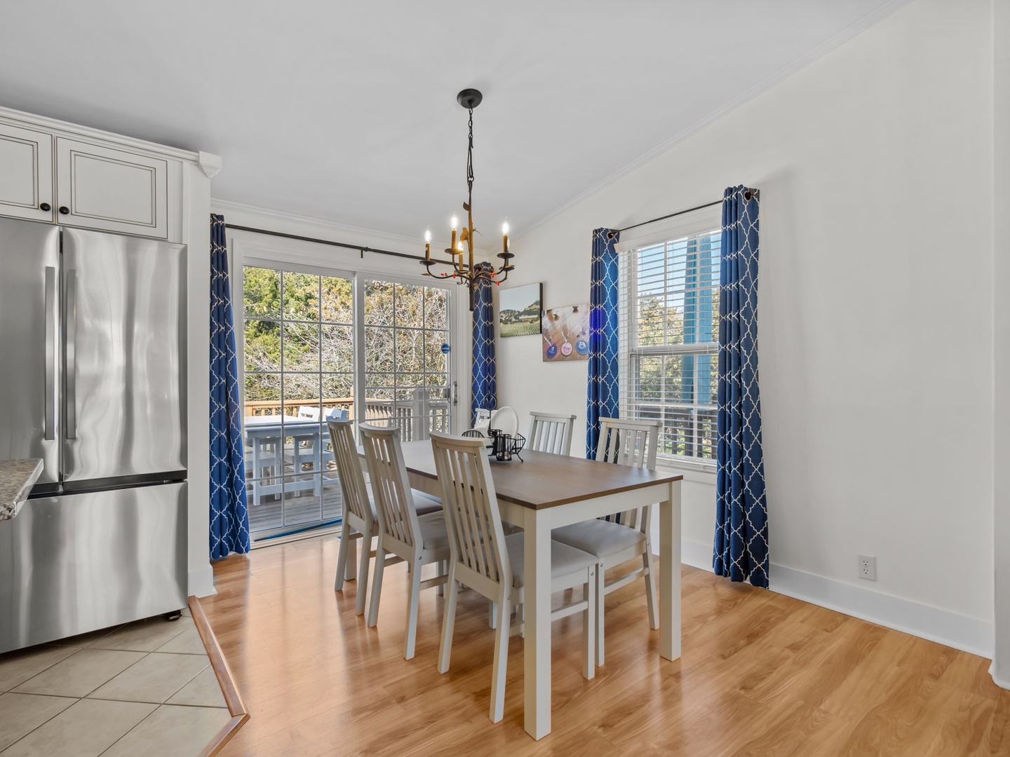 Gather around your bright dining table for memorable meals, with sunlight streaming through elegant blue curtains and city views beyond.