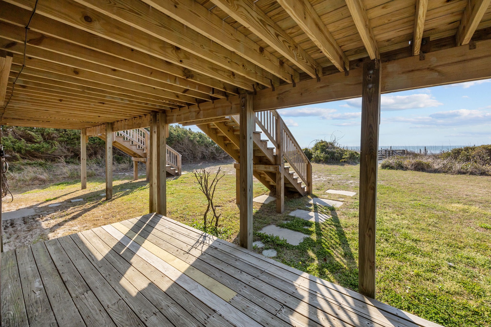 Step onto your private deck and feel the coastal breeze as sunlight filters through natural wood beams above.