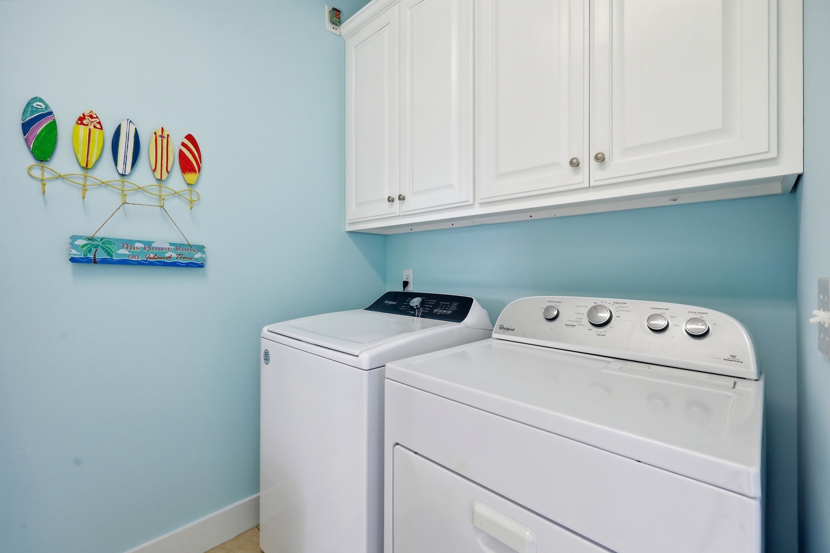 Keep your wardrobe fresh with your own in-unit washer and dryer. White cabinets provide convenient storage in this cheerful laundry space with coastal-inspired decor.