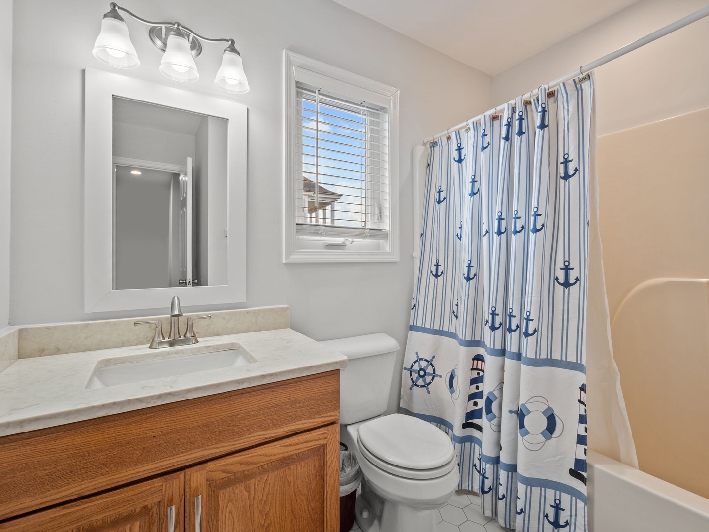 Refresh in your charming nautical bathroom featuring coastal-themed touches and bright natural light from the window.