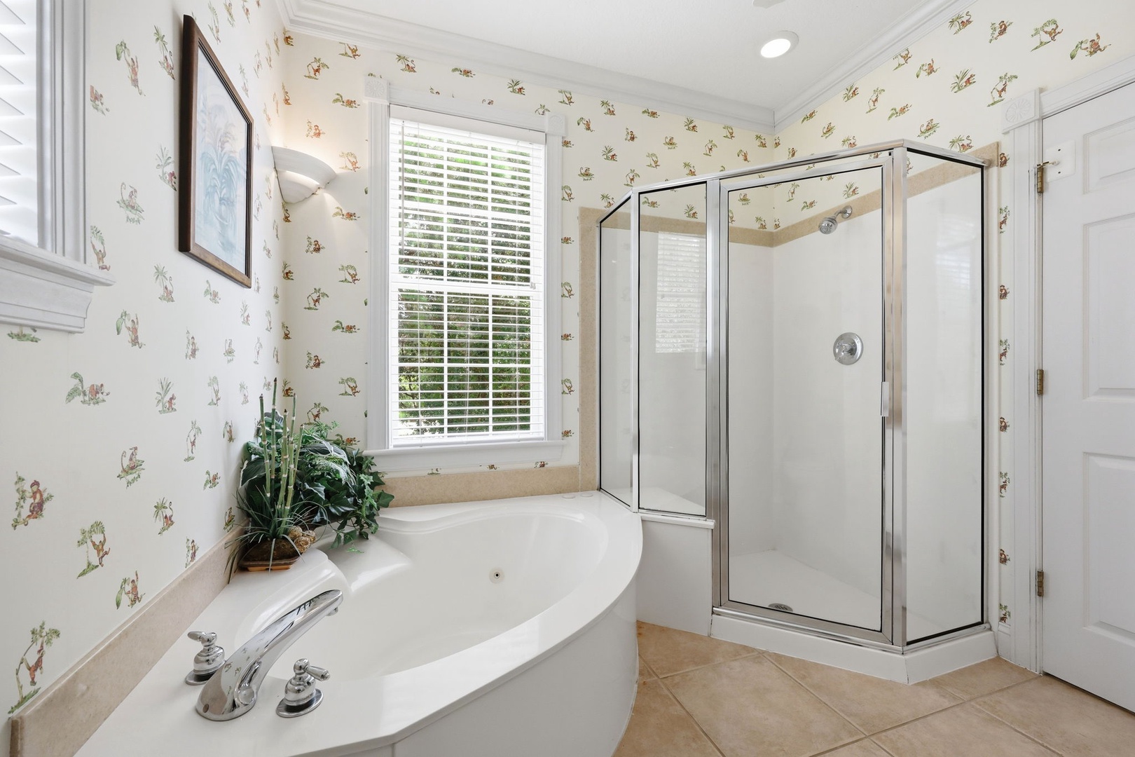 Unwind in your private bathroom retreat with a soaking tub and separate glass shower—charming floral wallpaper adds a cozy, cottage-inspired touch.