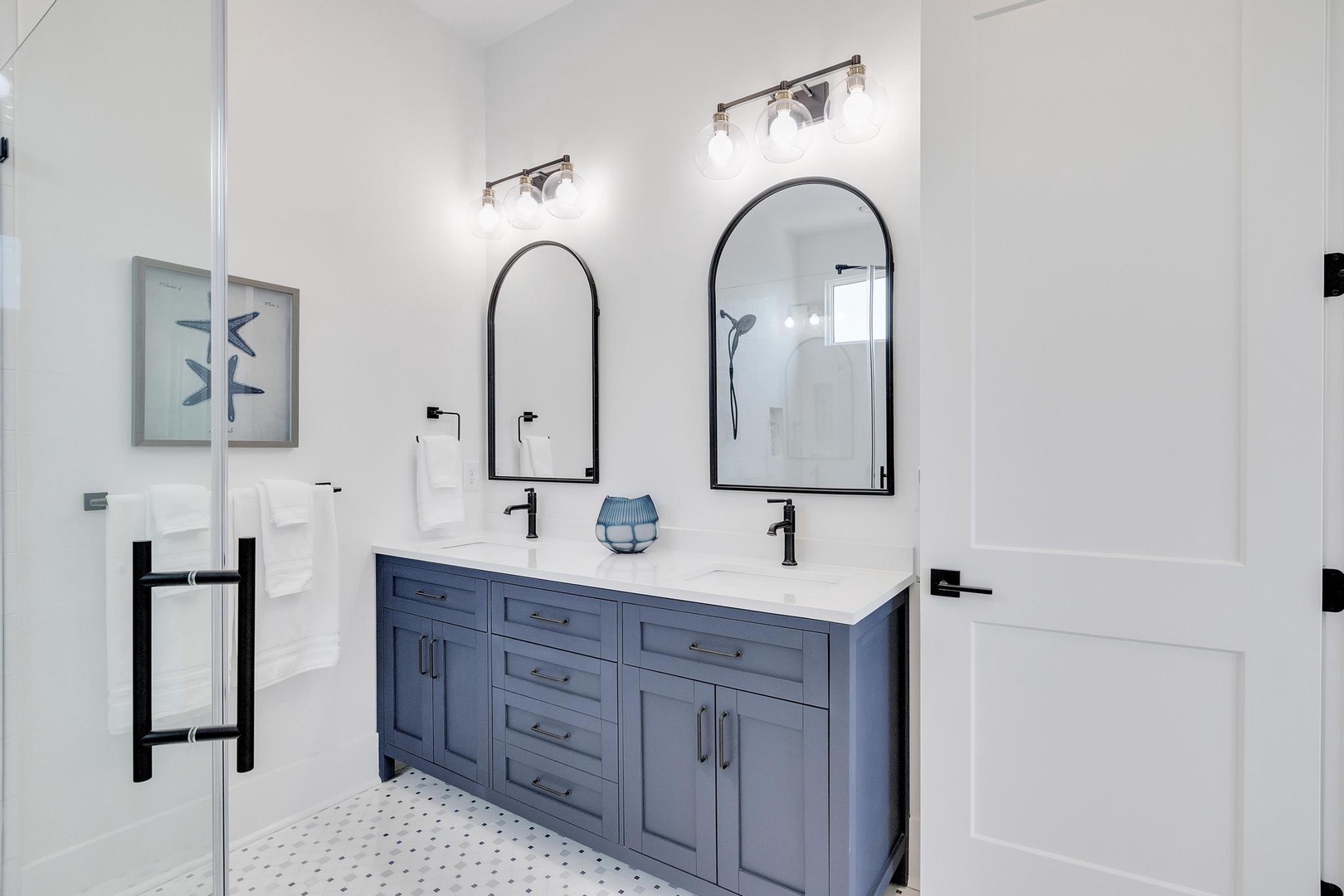 Refresh in your private bathroom featuring dual vanities, elegant arch mirrors, and modern fixtures that blend style with comfort.