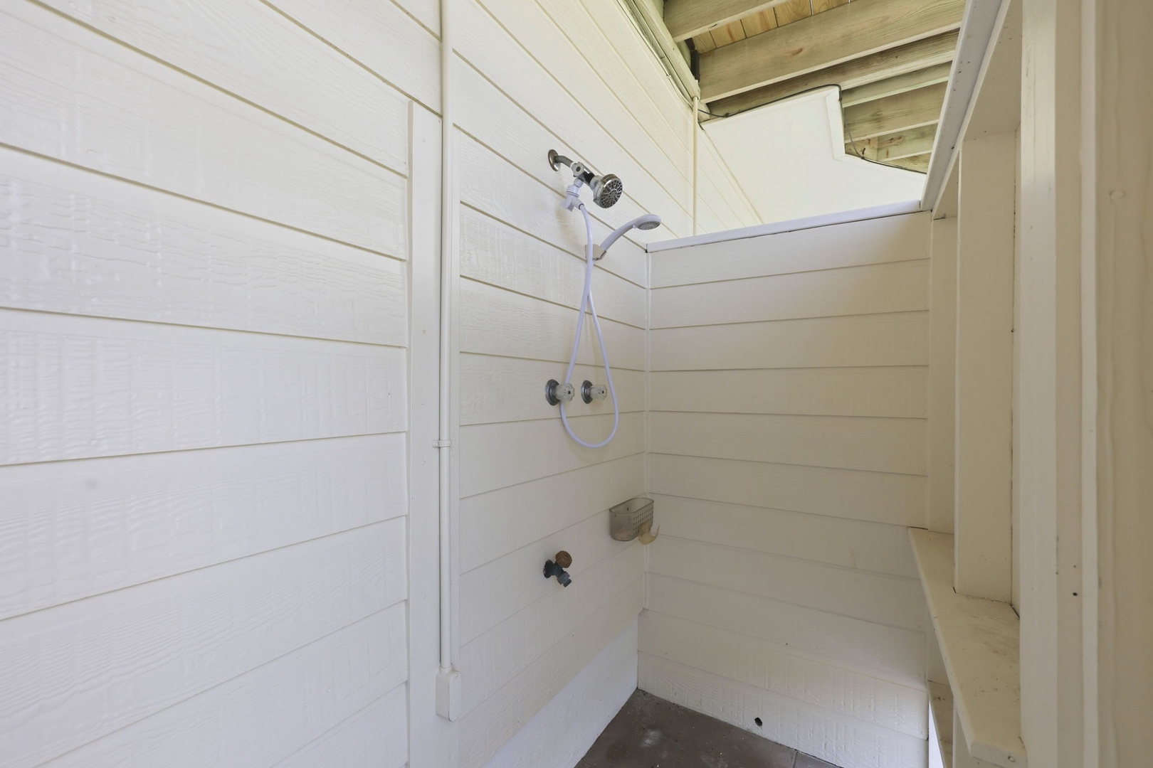 Step into your private outdoor shower, where rustic wood beams and fresh white shiplap create a refreshing escape after a day at the beach.