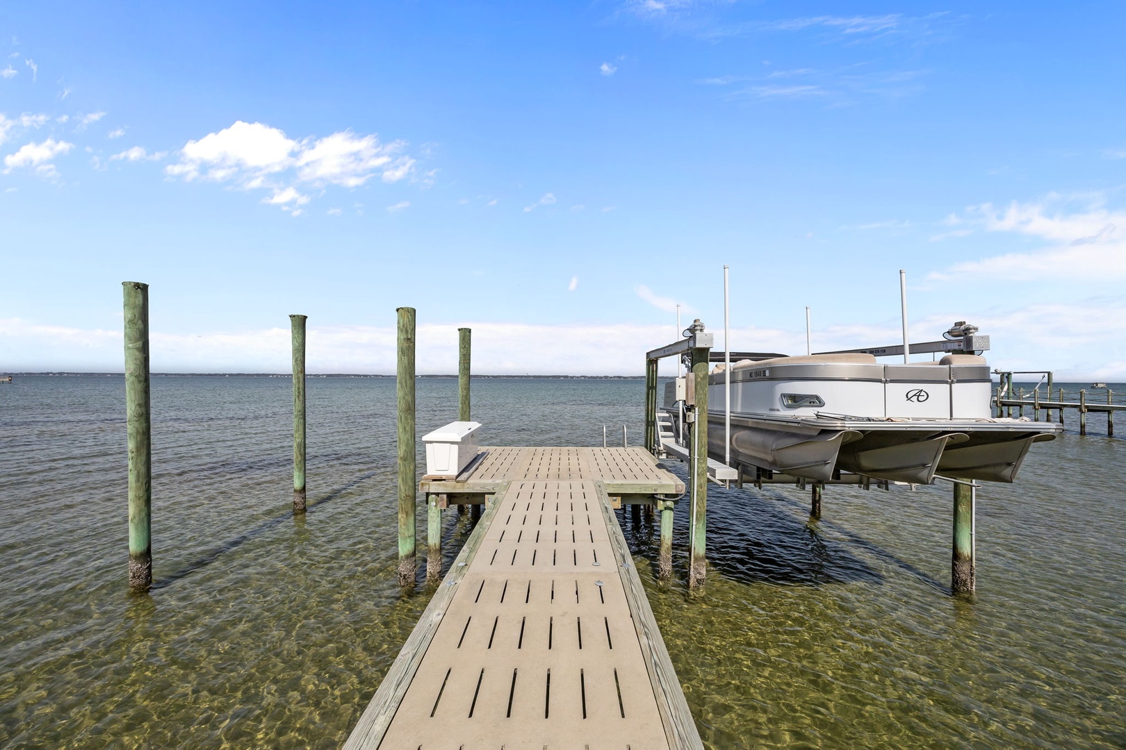 Private dock with boat access on crystal-clear waters under bright blue skies.