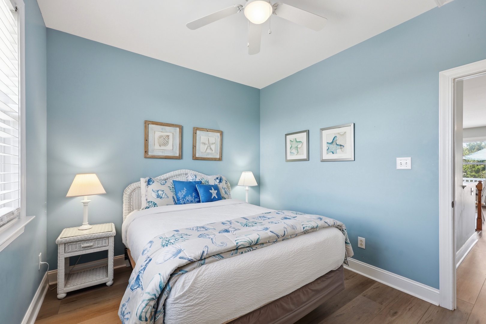 Drift off in your serene coastal-inspired bedroom, where calming blue walls and ocean-themed artwork create a peaceful retreat after a day of exploration.