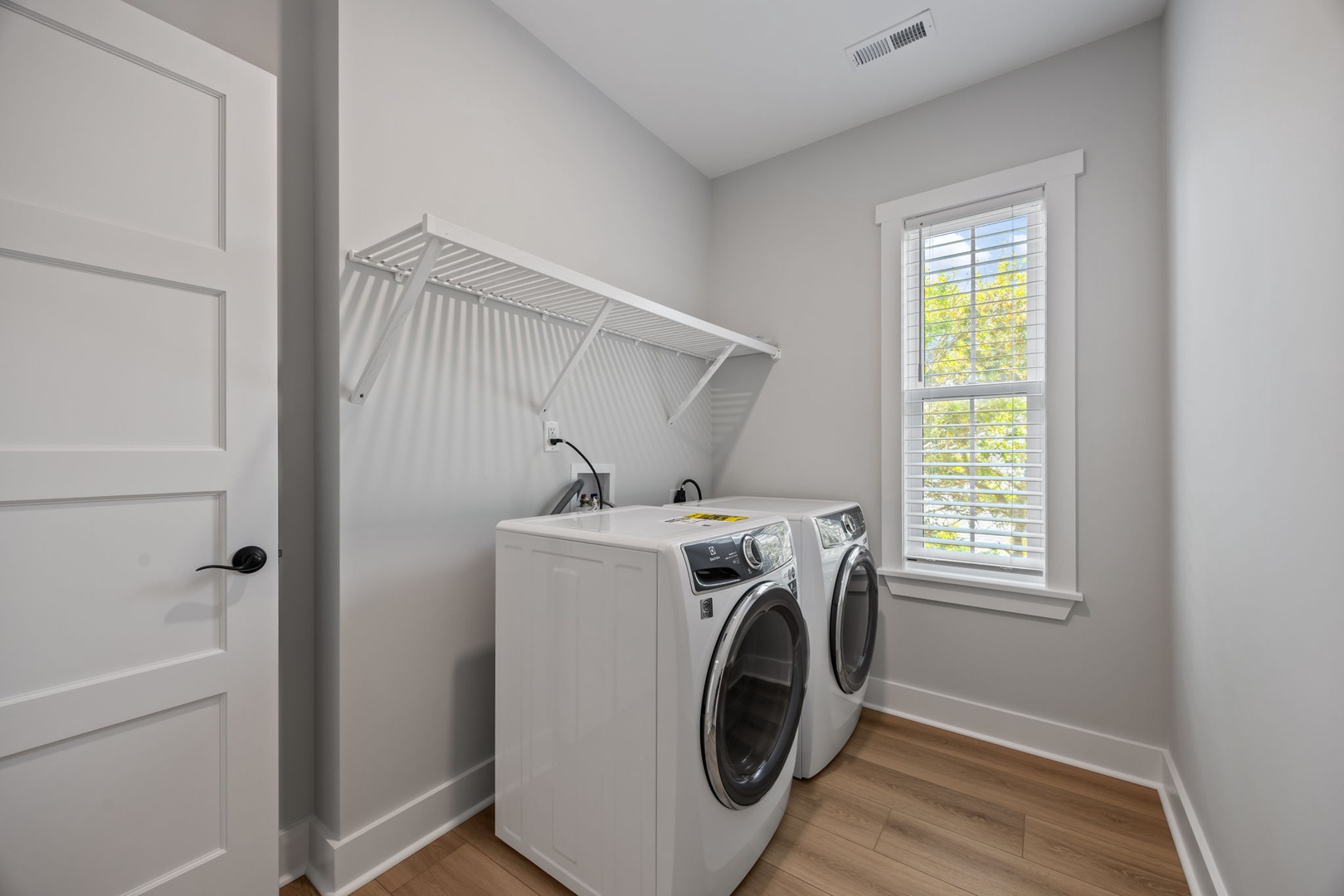 Keep your clothes fresh and clean in this bright, well-organized laundry room with modern machines and convenient hanging space.