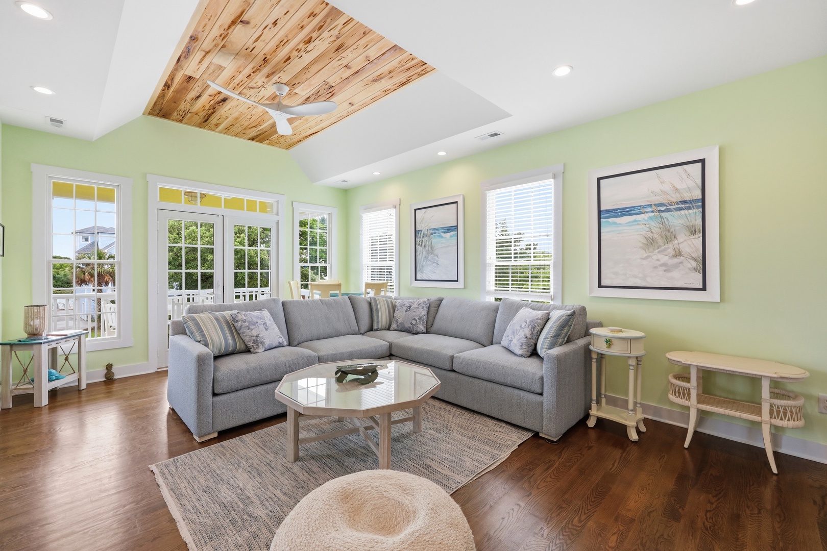 Unwind in your bright, coastal living room with vaulted wood ceilings, plush seating, and serene beach views framed by sunlit windows—your peaceful retreat awaits.