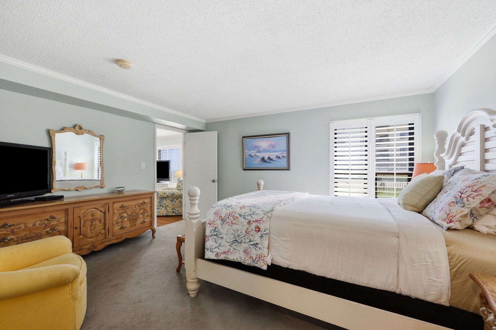 Picture yourself sinking into this plush bed after a day exploring, surrounded by soft coastal blues and charming vintage touches. Morning light filters through plantation shutters, inviting you to rest.