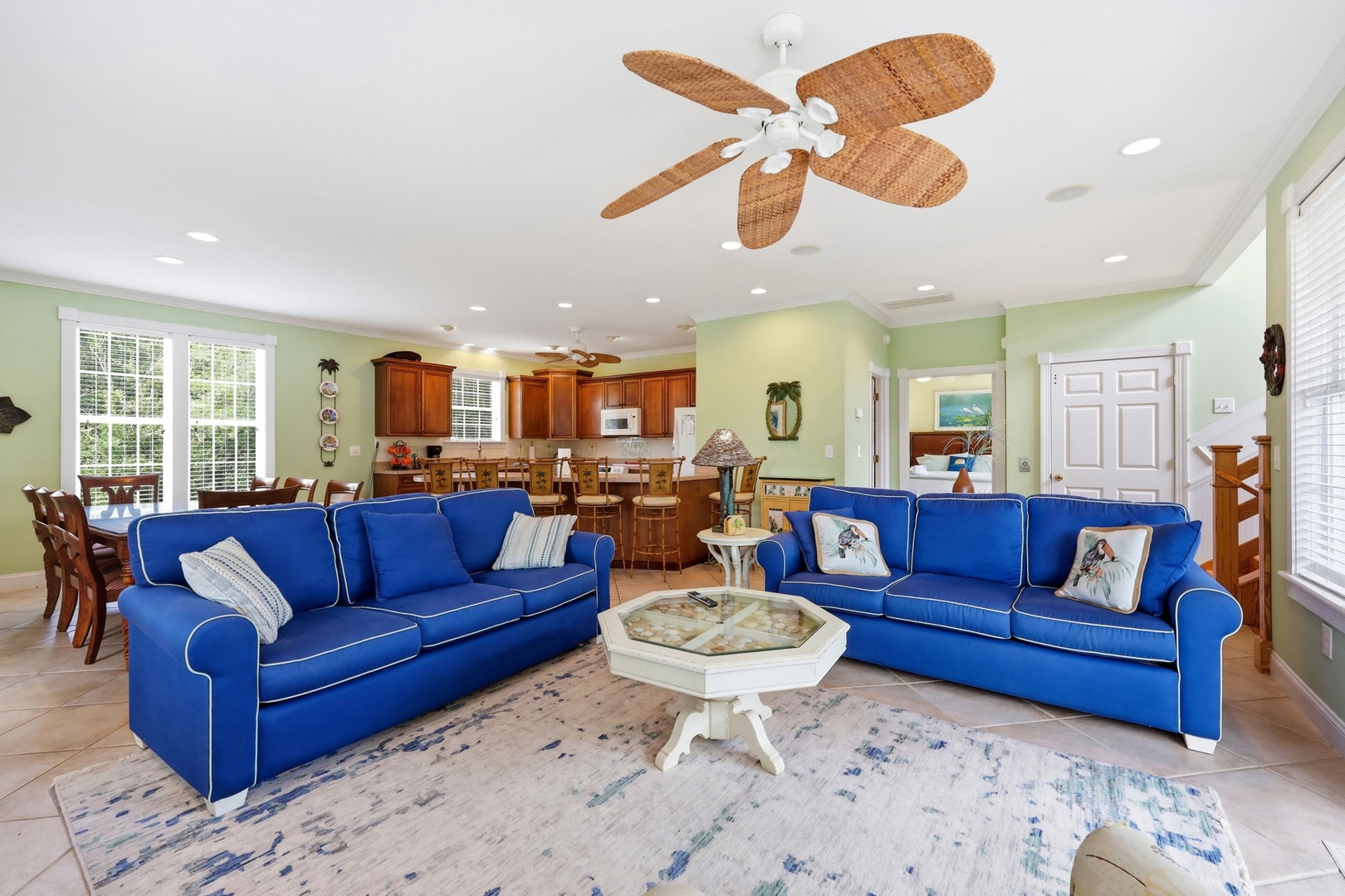 Bright coastal living awaits you in this spacious open-plan area with cheerful blue sofas, elegant dining space, and fully-equipped kitchen—perfect for gathering with loved ones.