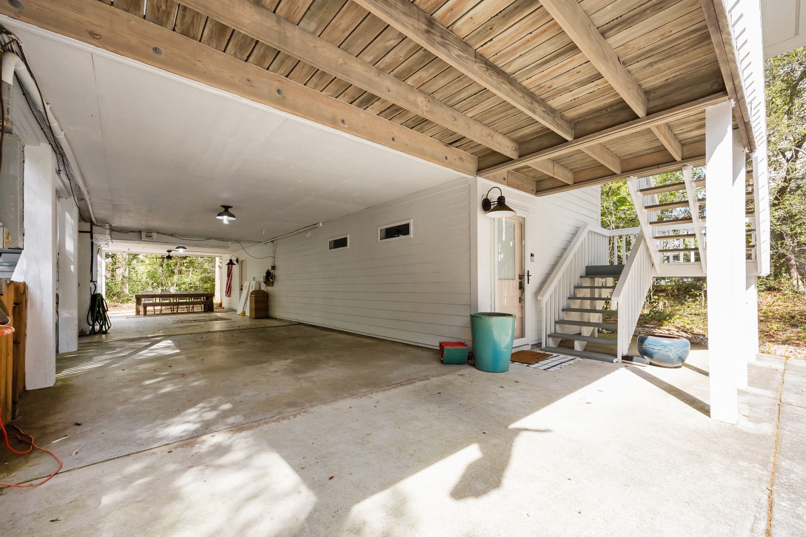 Spacious covered parking area provides convenient shelter for your vehicles with exposed beam ceiling and nearby staircase access.