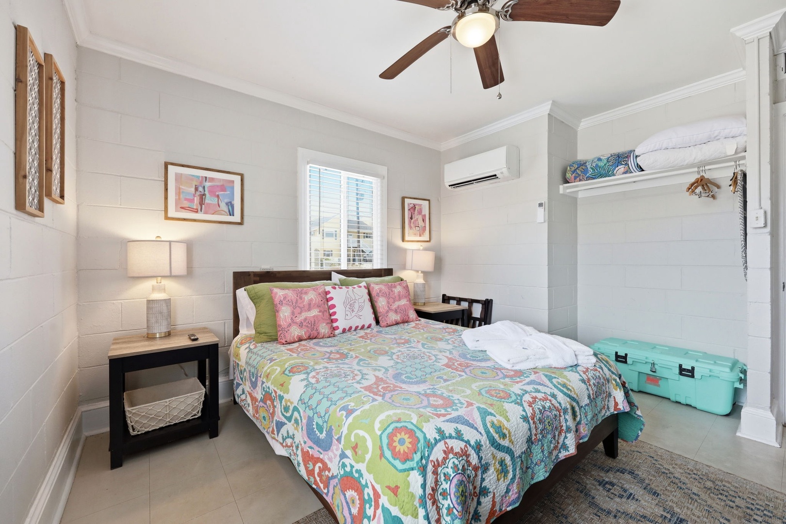 Unwind in your coastal retreat with a plush bed dressed in vibrant linens, ceiling fan to keep you cool, and a cozy reading nook by the window where you can relax after a day of exploring.