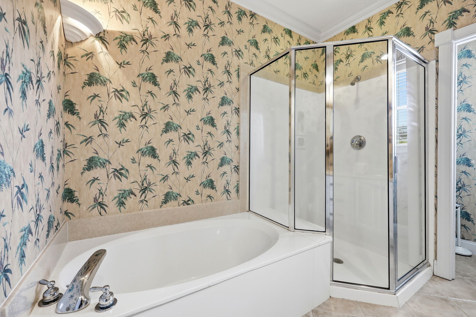 Spacious bathroom featuring a soaking tub and glass-enclosed shower, accented with charming botanical wallpaper to create your tranquil retreat.