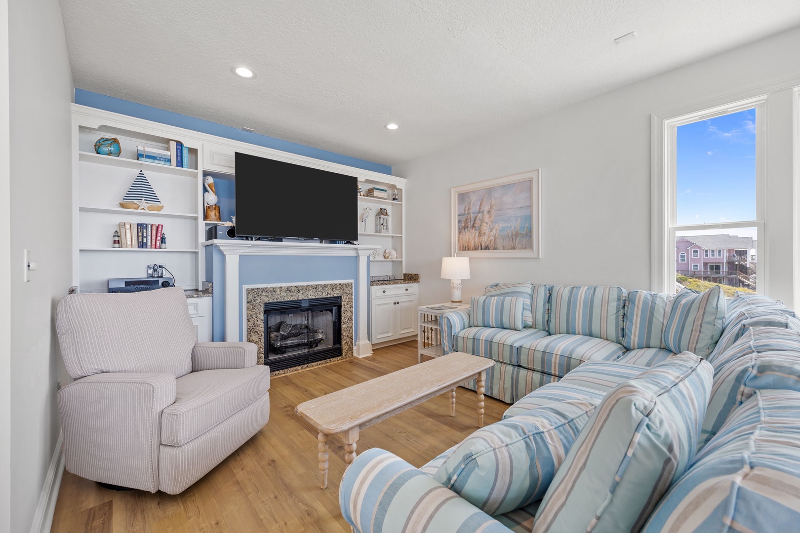 Sink into coastal comfort in your bright living room, where built-in shelves showcase local treasures and the fireplace invites cozy evenings.