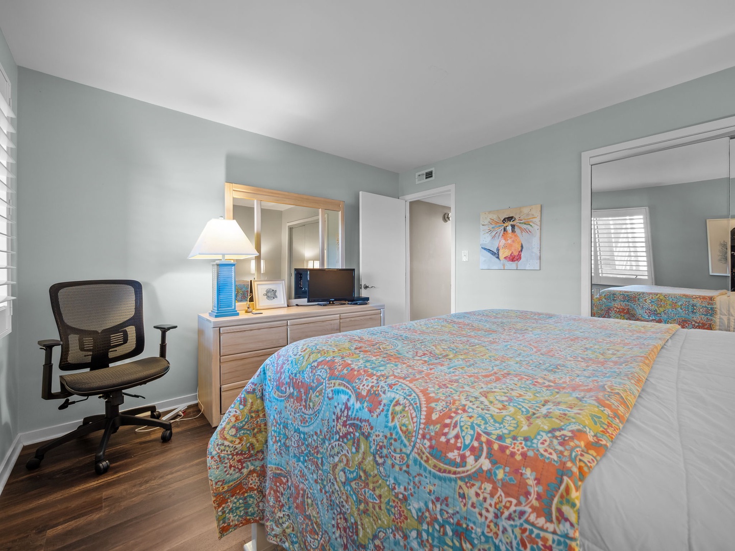 Your peaceful bedroom sanctuary features colorful bedding, natural light, and a dedicated workspace for ultimate comfort.
