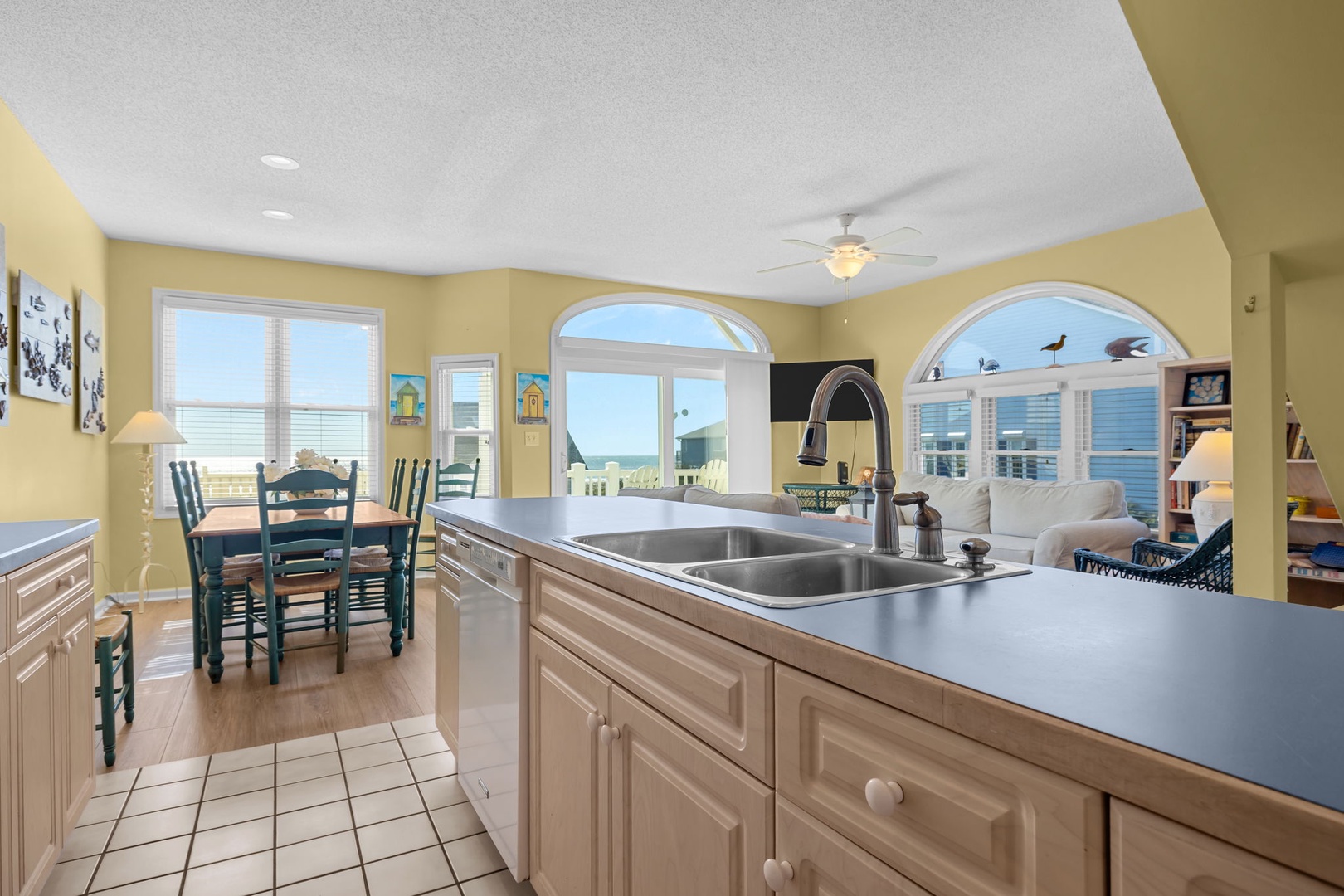 Your coastal kitchen flows seamlessly to the living area with stunning ocean views through arched windows and French doors.