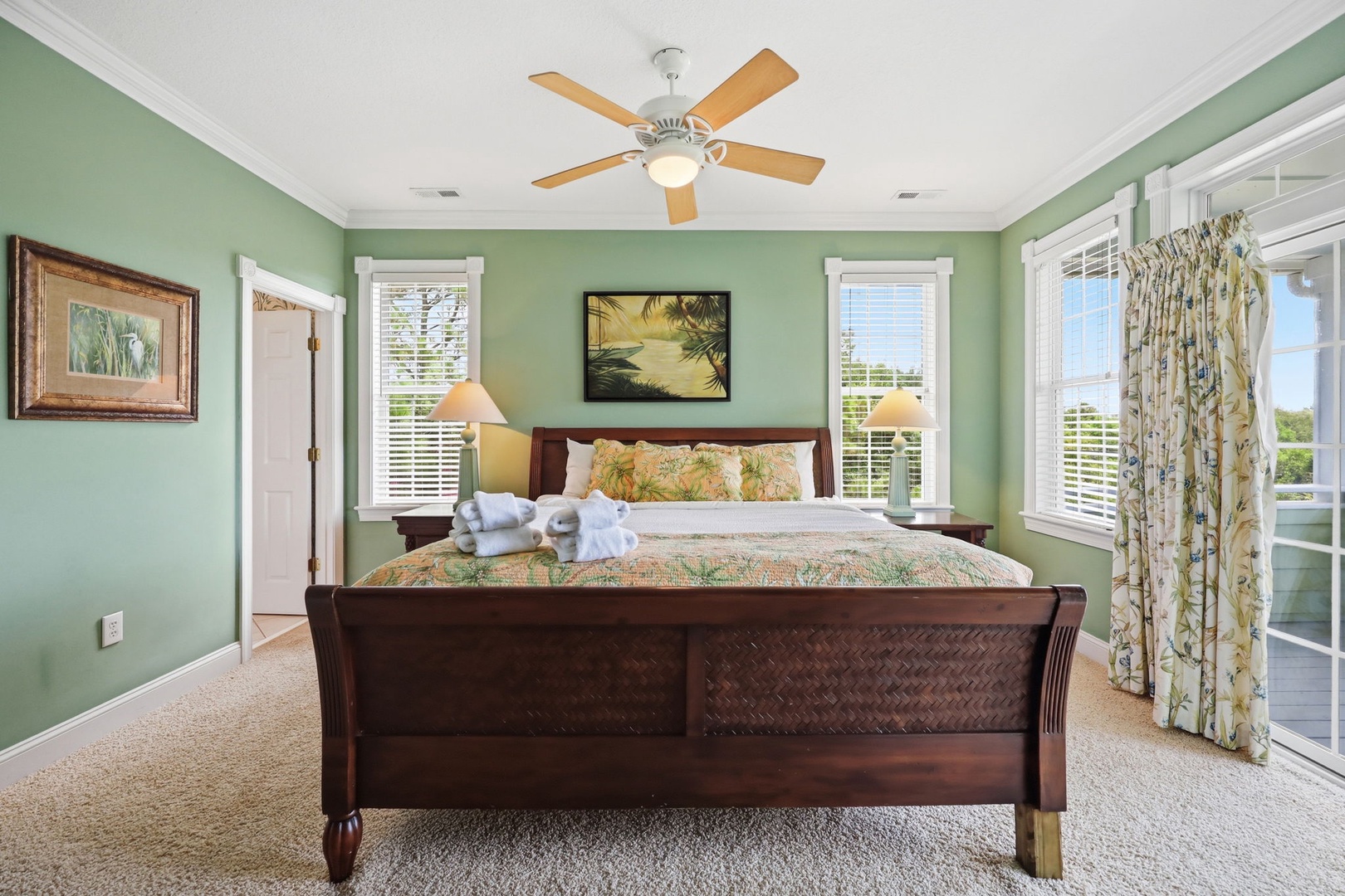 Unwind in your serene retreat with soft sage walls, a plush king bed, and gentle ceiling fan breeze. Natural light fills the space while balcony doors invite fresh air and tropical views.