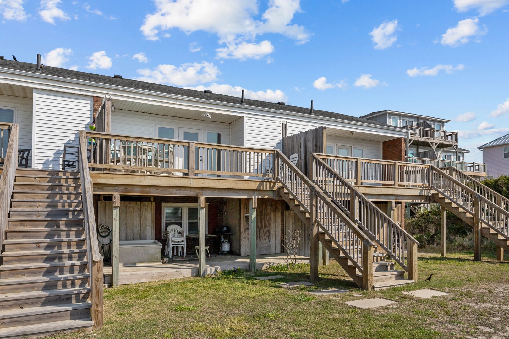 Coastal beach house with elevated wooden decks and stairs leading to comfortable accommodations in a peaceful seaside neighborhood.