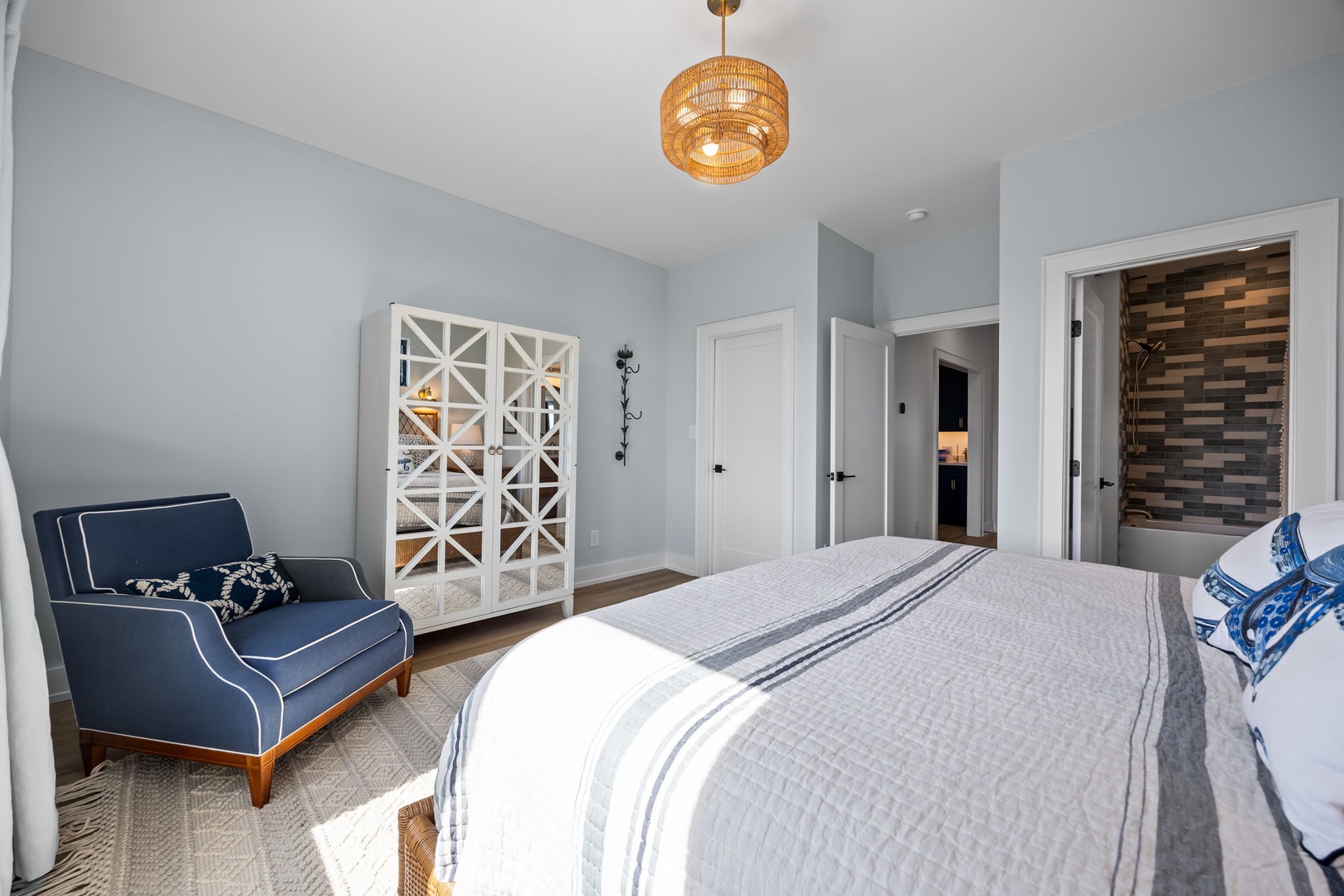 Unwind in your beautifully designed bedroom featuring soft linens, a cozy reading chair, and charming coastal touches that create the perfect retreat.